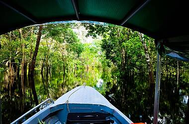 Blick nach vorne aus einem überdachten Boot der Turtle Lodge auf einem überfluteten Fluss im Amazonasdschungel in Brasilien